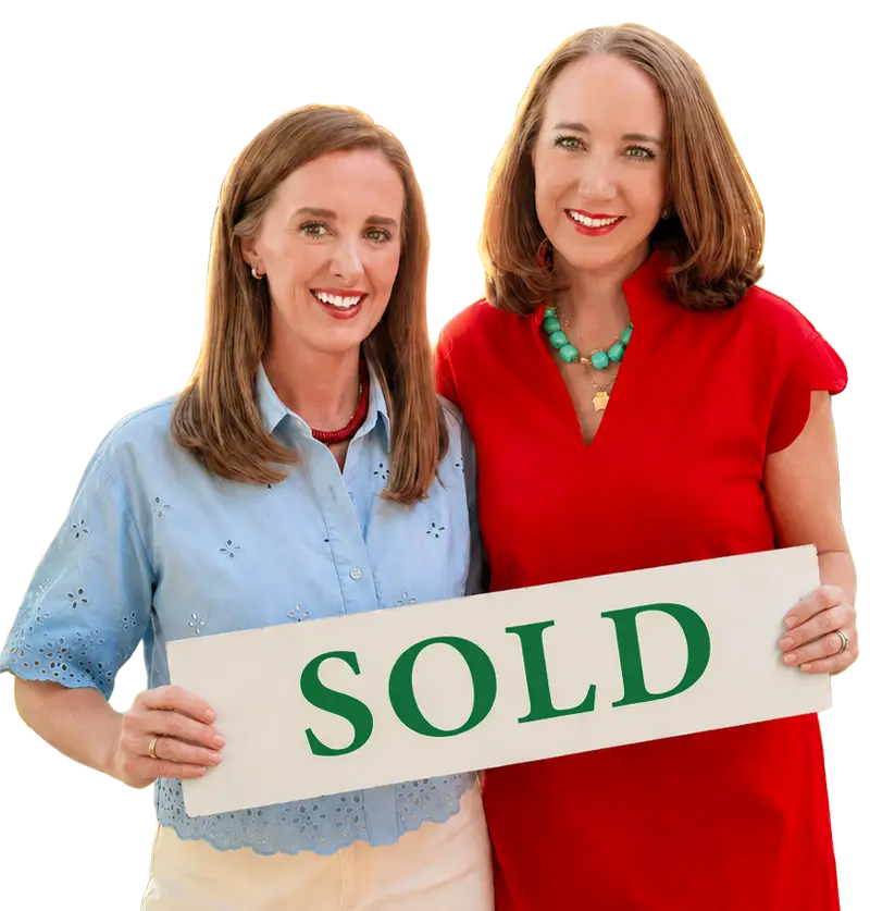 Katie and Callie smiling and holding a white sign saying "SOLD" in green